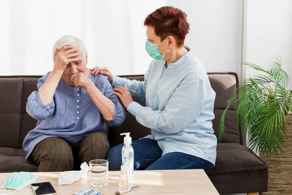 A caregiver comforts an older woman who is feeling unwell