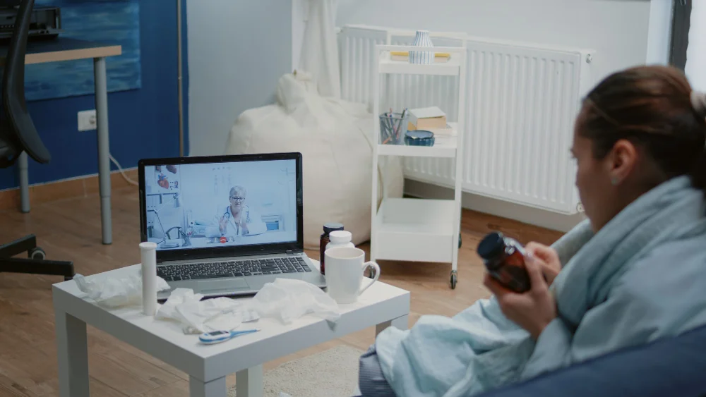 A patient at home has a video visit with a physician on a laptop