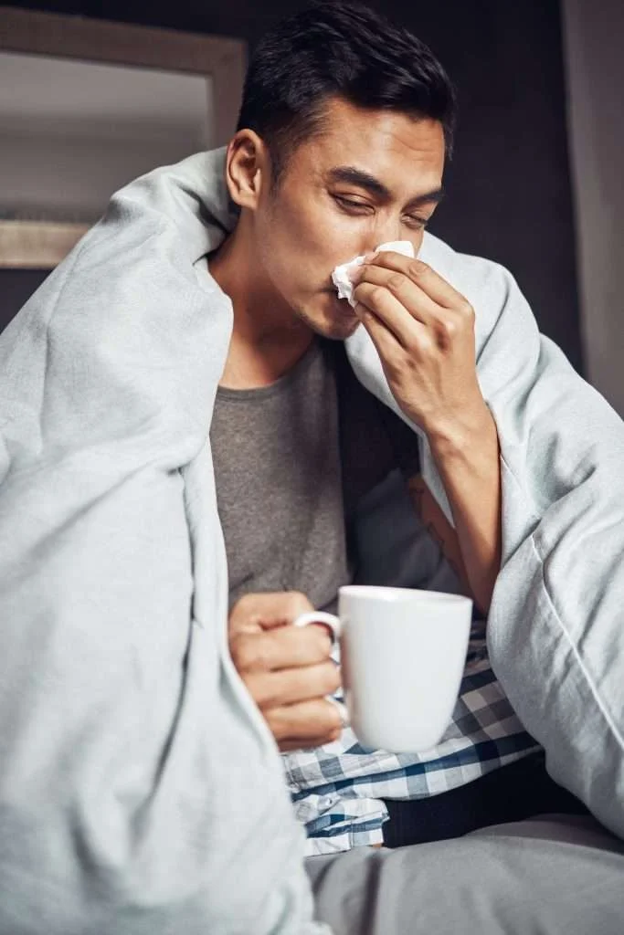Acute Care Visits 2 dont get flu get shot shot young man blowing his nose having tea while recovering from illness bed home