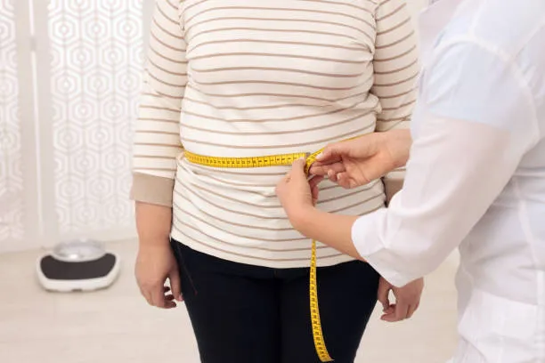 A clinician measures a patient’s waist with a tape measure